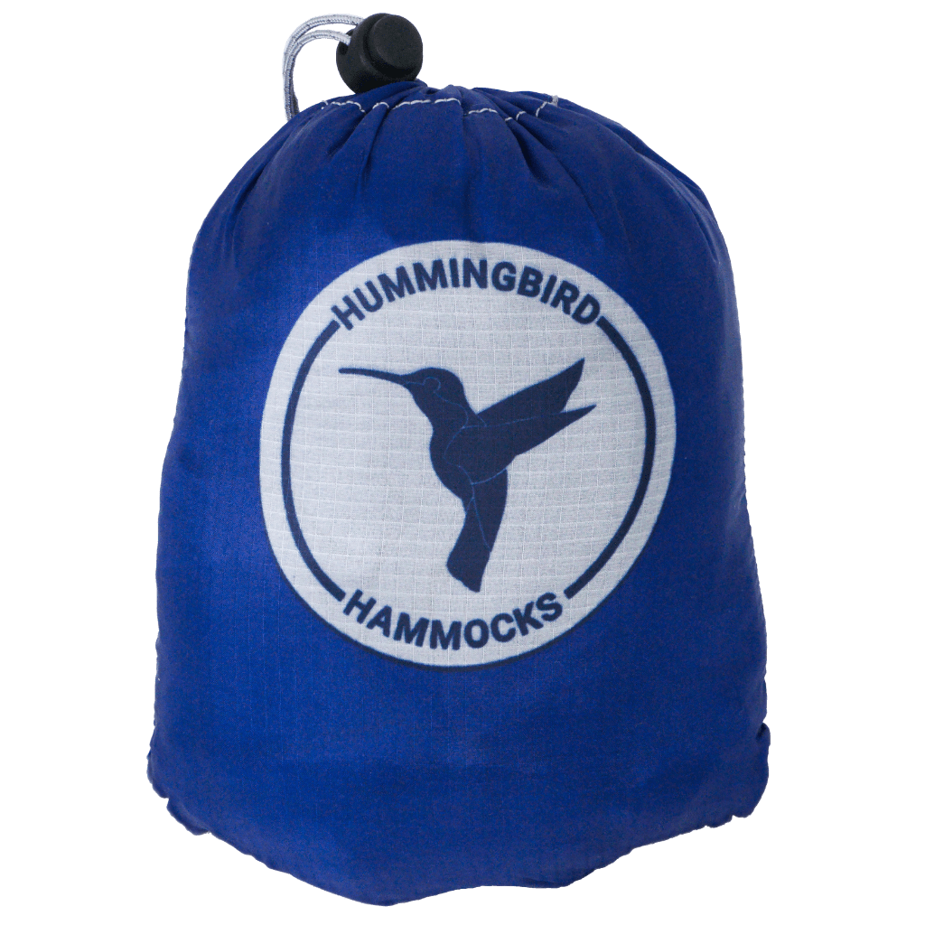Blue drawstring bag with the "Hummingbird Hammocks" logo featuring a silhouette of a hummingbird in a circular design, designed by an FAA Certified Parachute Rigger.
