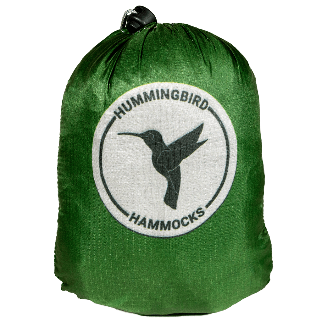 Green stuff sack with the logo of "Hummingbird Hammocks" featuring a black silhouette of a hummingbird on a white circle and marked by an FAA Certified Parachute Rigger for the Long Hammock.