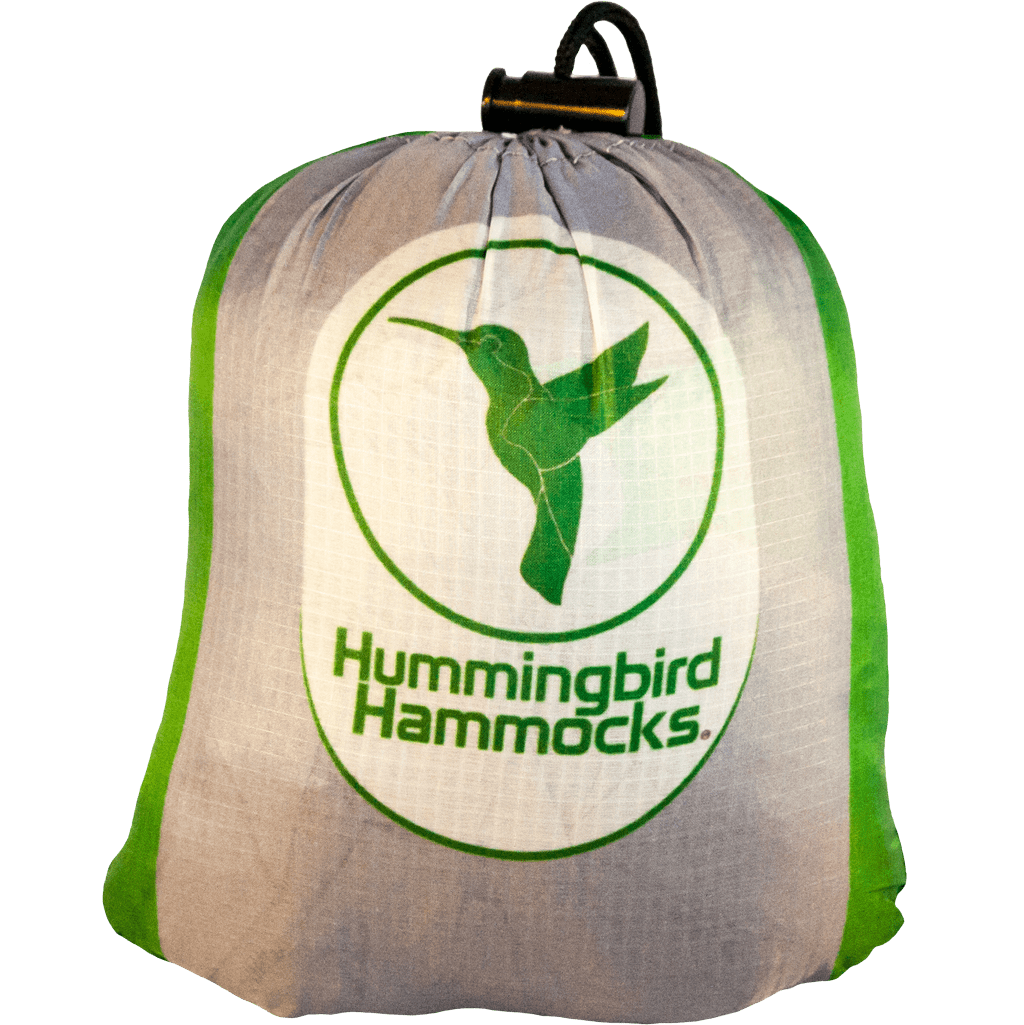A double hammock branded with "Hummingbird Hammocks" and a hummingbird icon, displayed against a green background, designed by an FAA Certified Parachute Rigger.