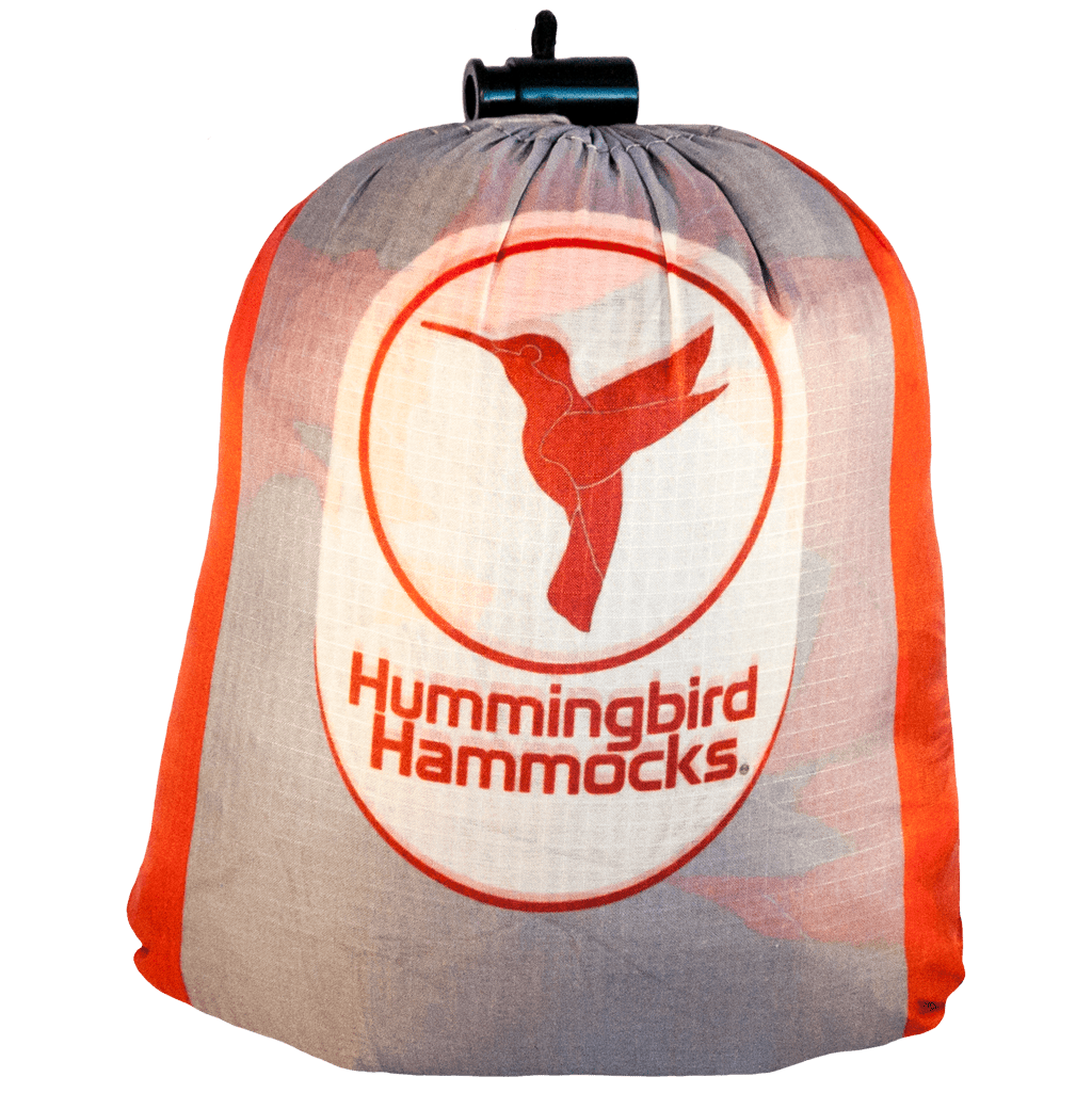 A lightweight, collapsible Hummingbird Hammocks Ultralight Double Hammock in a drawstring storage bag with the Hummingbird Hammocks logo featuring a stylized hummingbird.