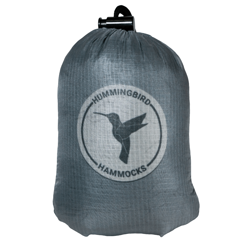 A gray drawstring bag with the Hummingbird Hammocks logo featuring a silhouette of a hummingbird in flight on a green background, equipped with the Ultralight Single+ Hammock attachment system.