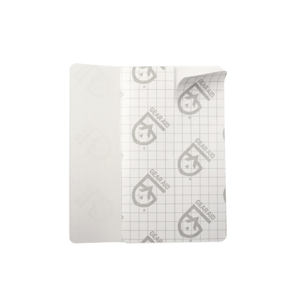 A crumpled piece of graph paper with a repetitive pattern of a branded logo, patched with Hummingbird Hammocks Tenacious Tape Max Flex Patches.