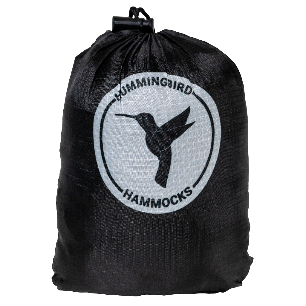 Black drawstring bag with Hummingbird Hammocks logo featuring a hummingbird silhouette, against a green background with Warbler Bug Net protection.