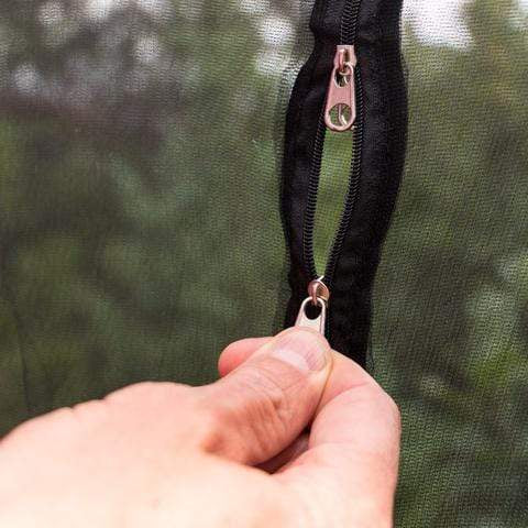 A hand zipping up a black zipper on a Warbler Bug Net by Hummingbird Hammocks background.