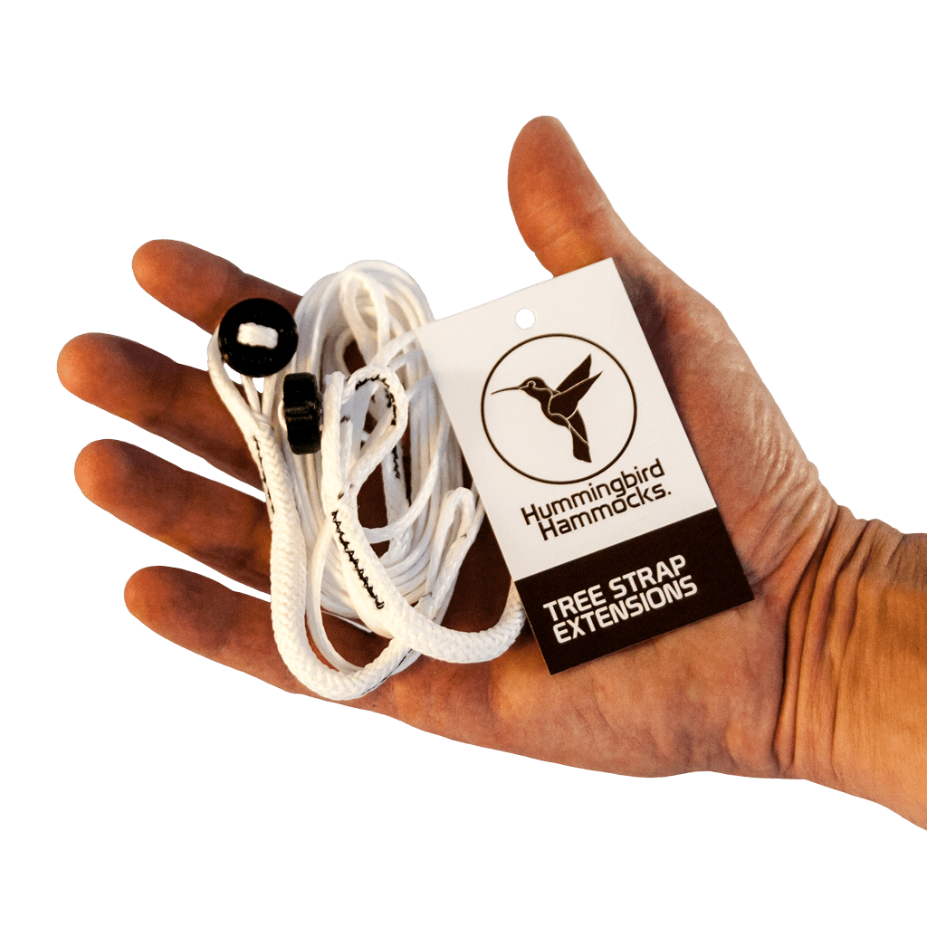 A hand holding a packaged set of Hummingbird Hammocks Ultralight Tree Strap Extensions, featuring a labeled card with a hummingbird logo.