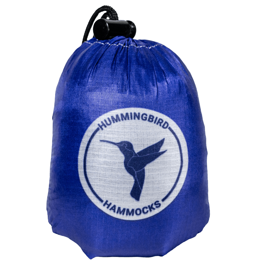 A blue drawstring bag with the "Hummingbird Hammocks" logo featuring a silhouette of a hummingbird in white on the front, utilizing parachute technology.