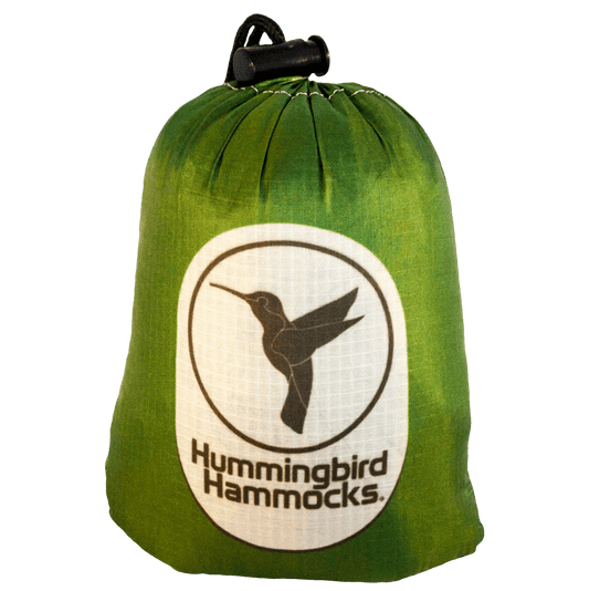 Green Ultralight Hummingbird Hammocks Single+ Hammock packed in a compact drawstring bag with the "Hummingbird Hammocks" logo featuring a hummingbird silhouette.