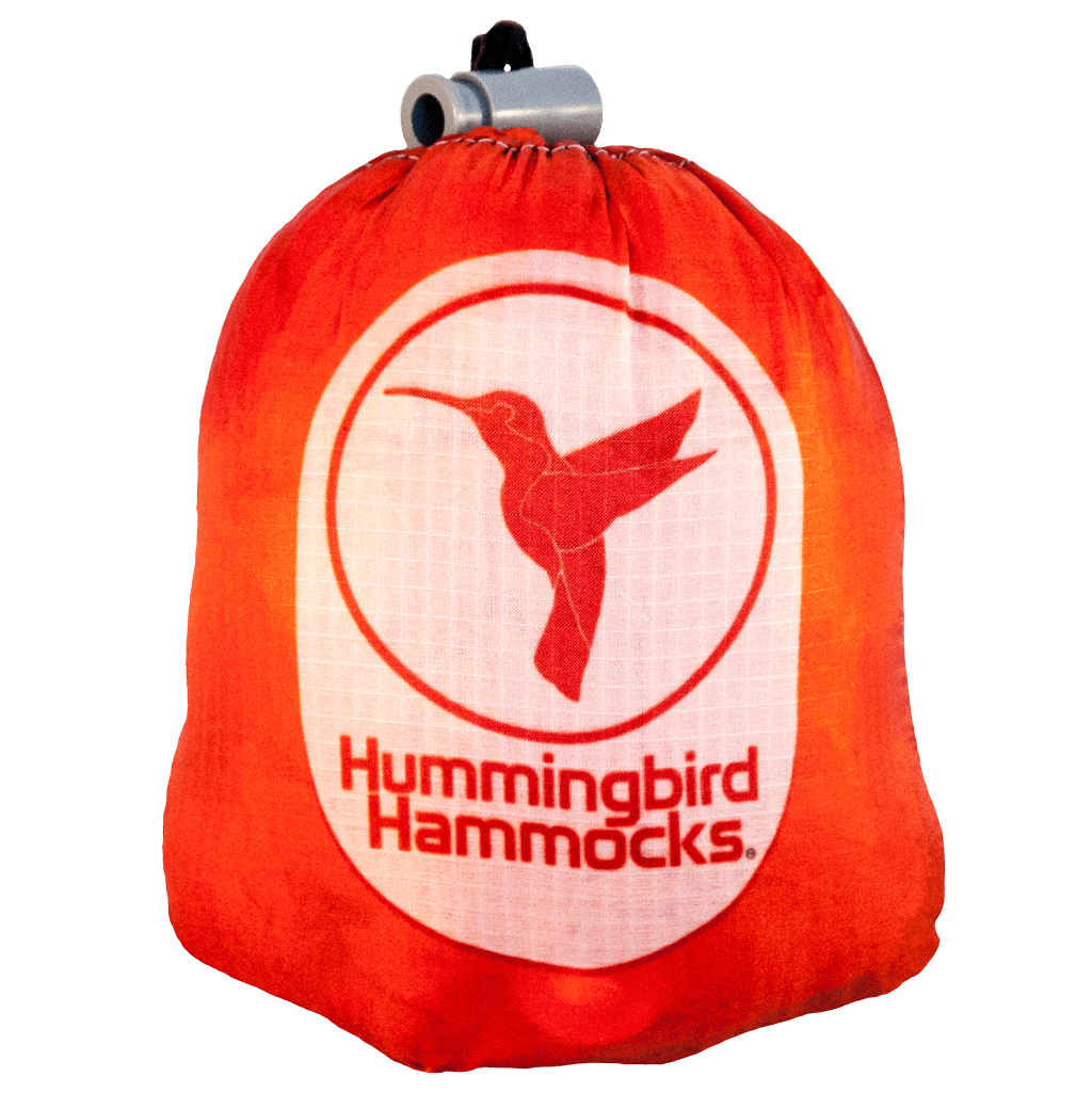 Orange stuff sack with a white logo of a hummingbird and the text "Hummingbird Ultralight Single Hammock by Hummingbird Hammocks.