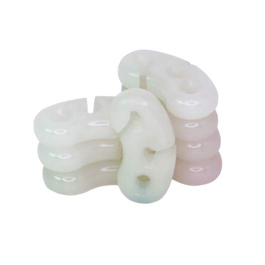 Transparent silicone rubber pads shaped like uppercase letters, made by injection molding, arranged on a green background.