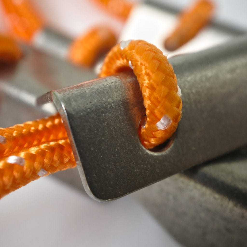 Close-up of an orange, reflective sleeved Hummingbird Hammocks Spectra Guyline Kit threaded through a metal clamp, highlighting the texture of the cord and the metallic sheen of the clamp.